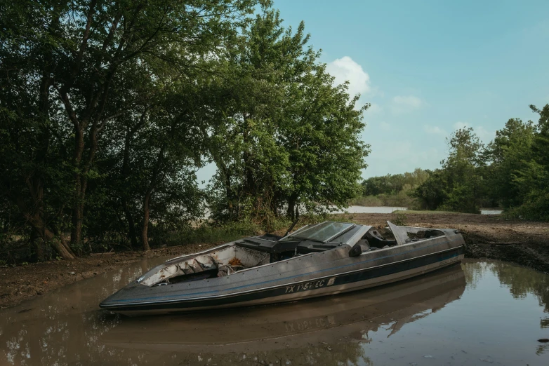 there is a black boat on the muddy shore