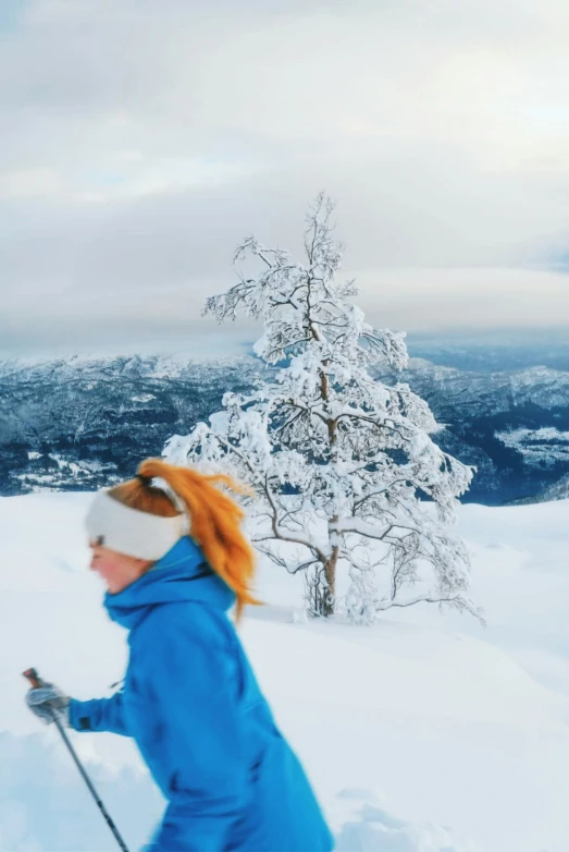 the person is walking in the snow, wearing a blue coat