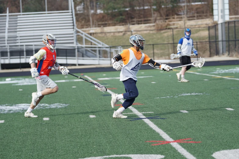 a man holding lacrosse sticks while standing on a field