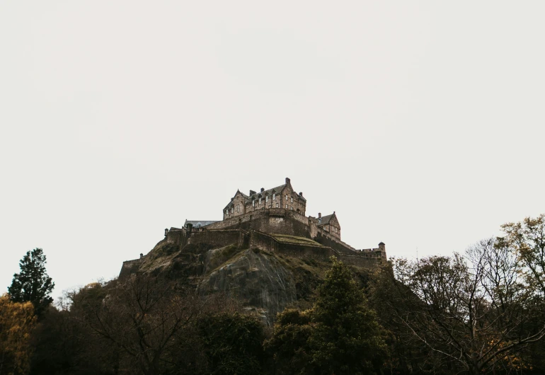 a castle with a clock at the top is on a hill