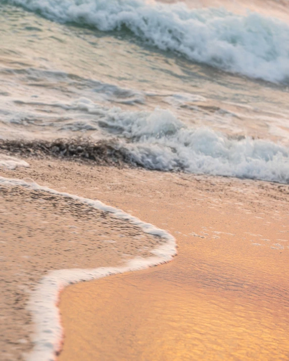 a wave rolls towards the sandy shore with foamy surf