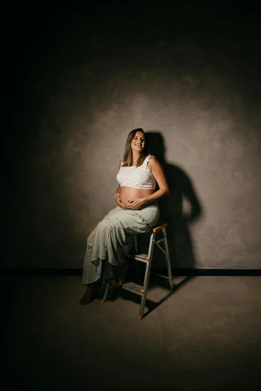 a pregnant woman sitting in a chair by a wall