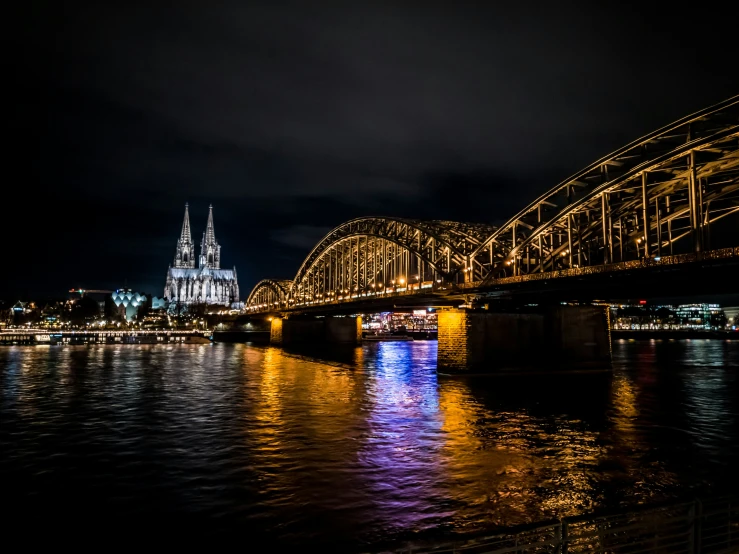 the bridge in front of a church is lit up at night