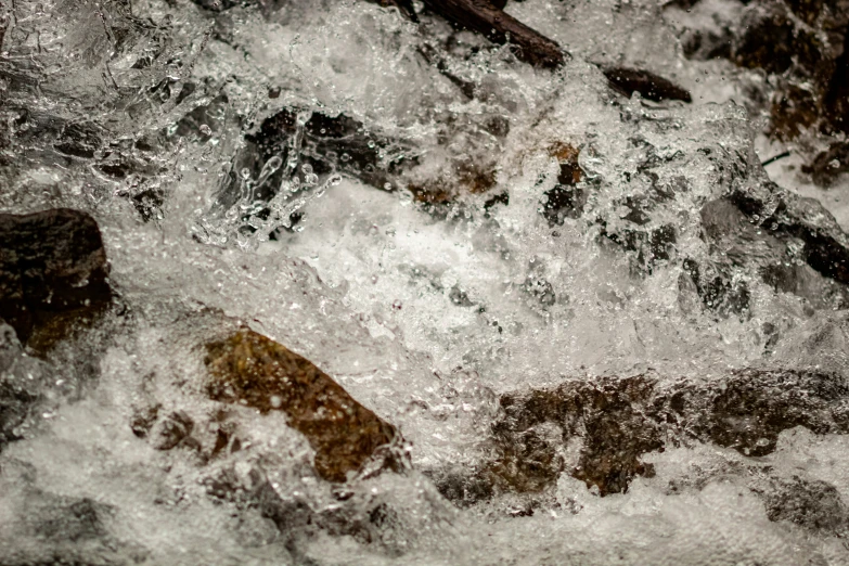 a small stream of water near rocks with a stick in it