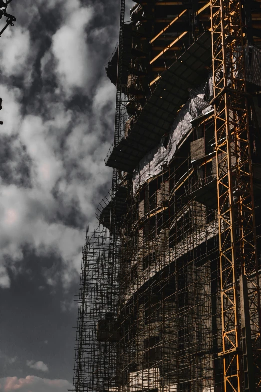 some scaffolding under cloudy skies and a plane