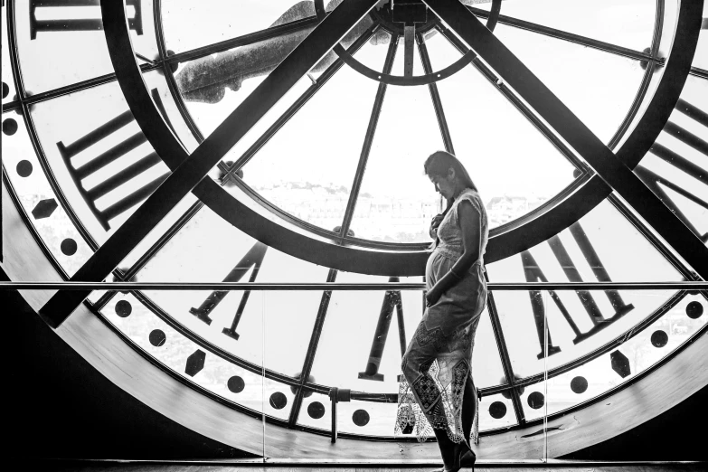 a man standing next to a big clock on a sunny day