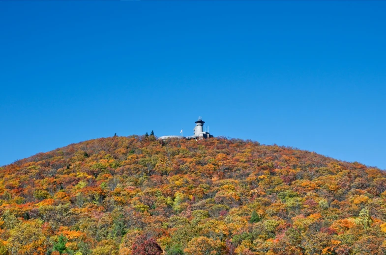 a lighthouse atop a colorful hill is seen in the background