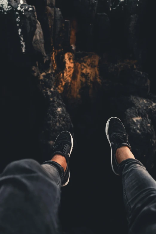 someone standing at the edge of a cave with their feet crossed and feet apart