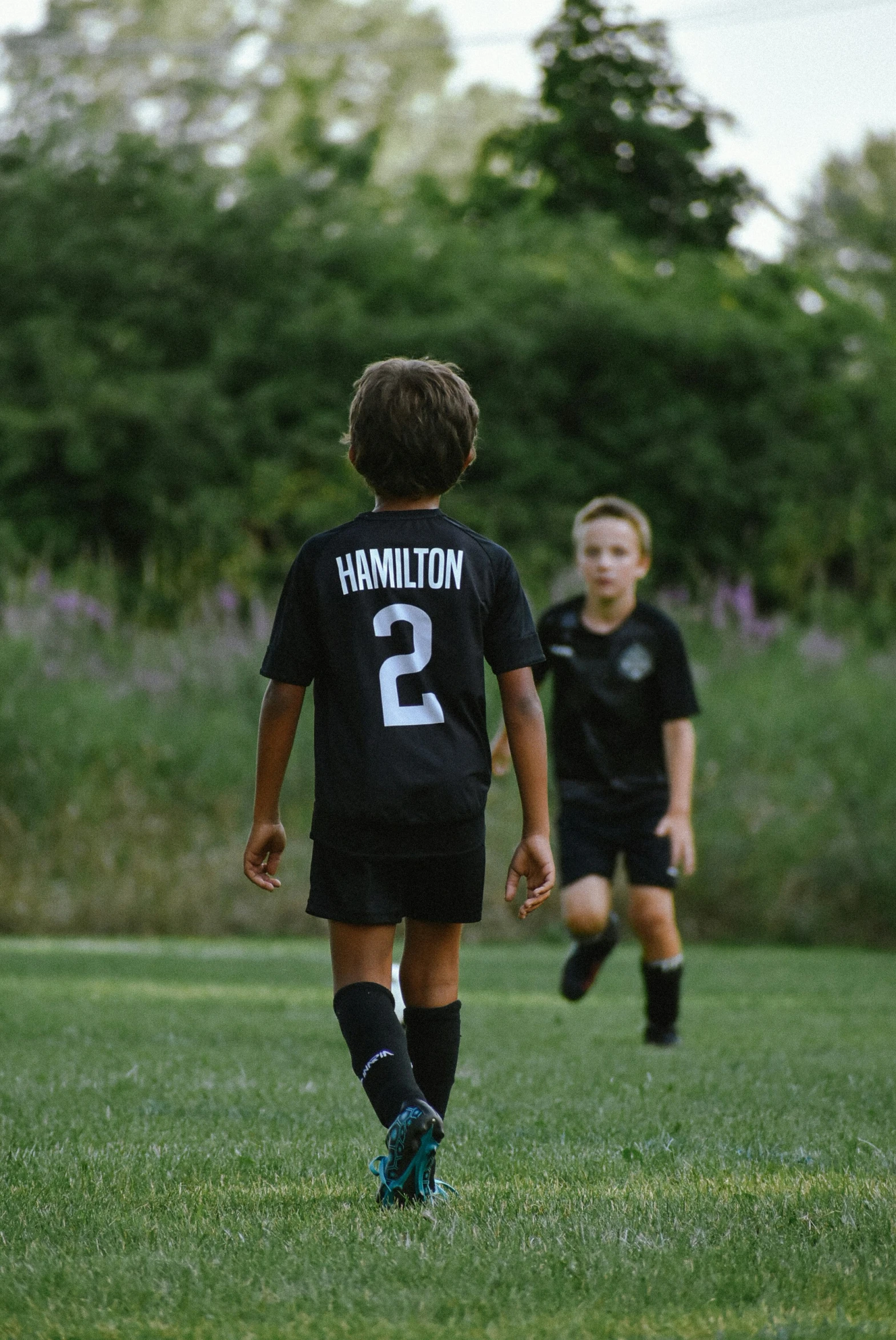 two boys playing soccer on a soccer field