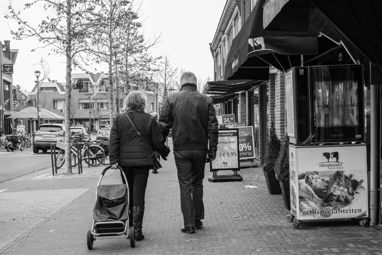 two people walking down a city street with a stroller