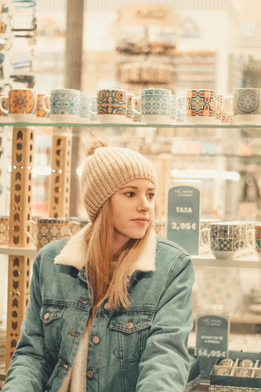 a girl with a knitted hat on standing near the shelves