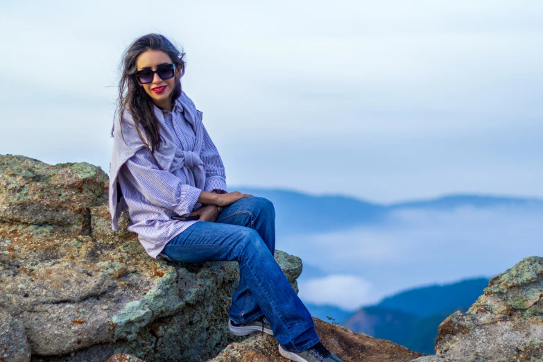 a woman sitting on top of rocks with sunglasses