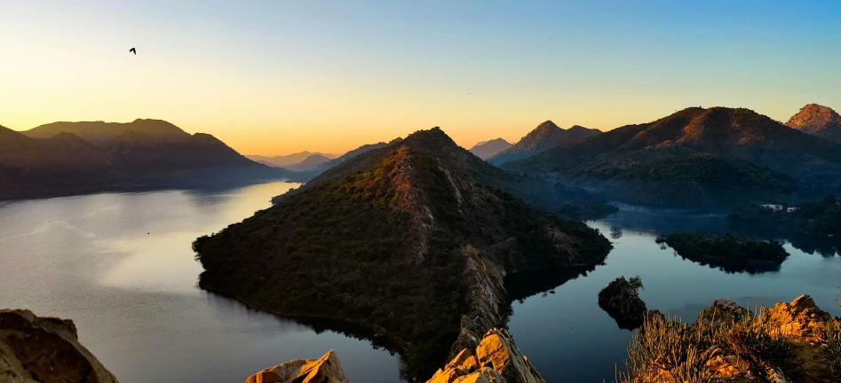 a bird flies over a rocky landscape on the water