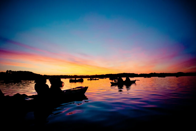 some people in a boat on water and at sunset