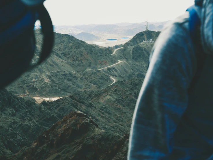 a man standing on top of a hill looking down at mountains