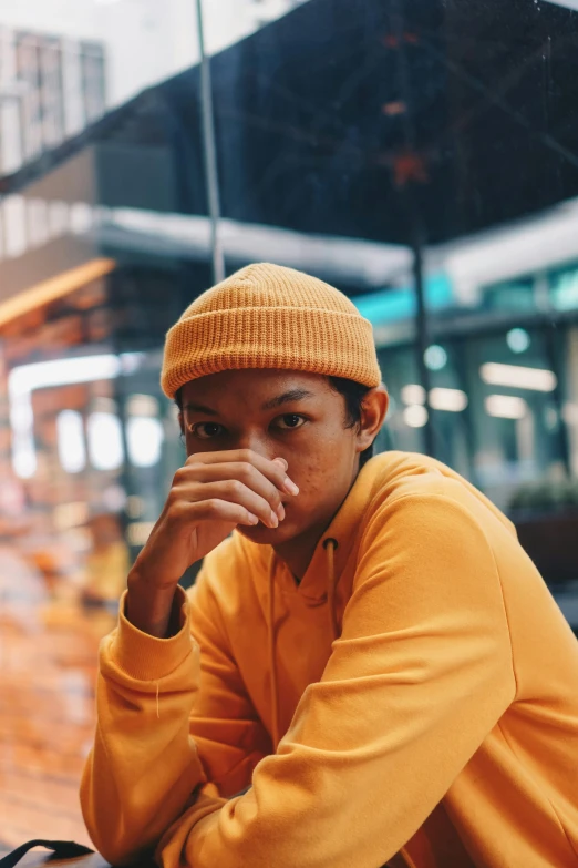 an african man wearing a mustard colored hat while sitting down