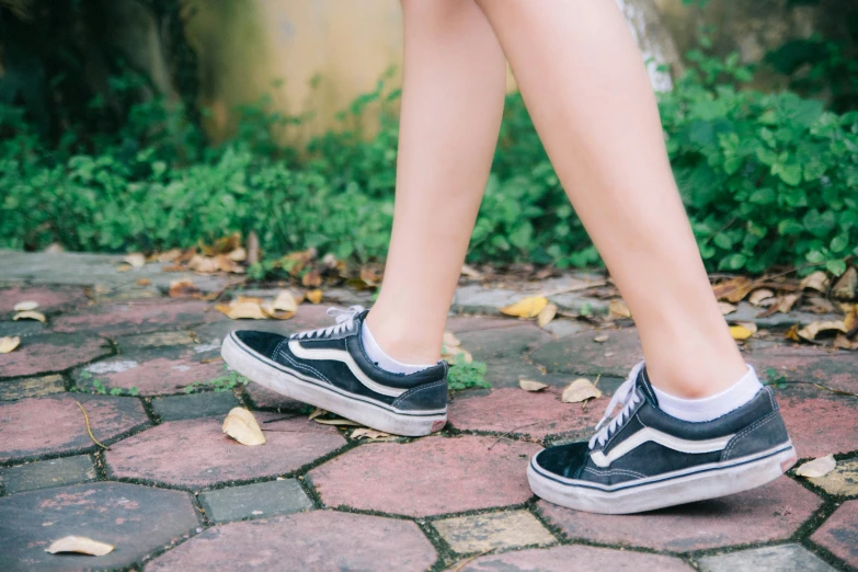 the feet of a young woman wearing shoes while walking