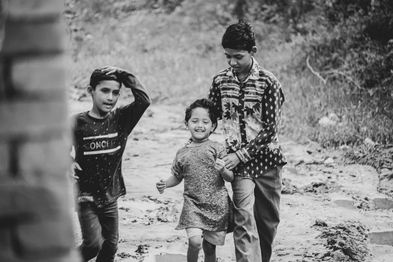 two children, one holding his head on another, are standing on the dirt road