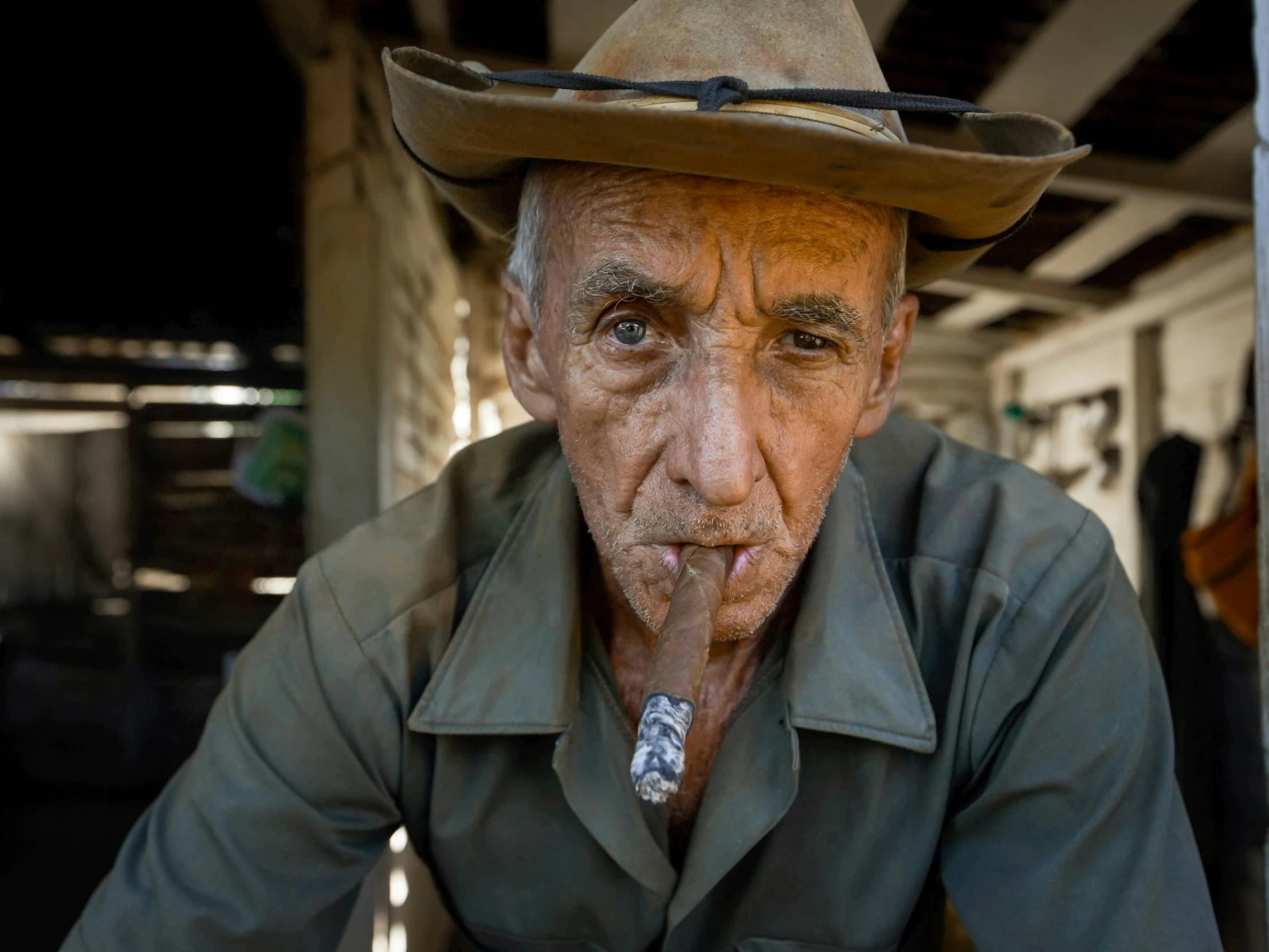 a man wearing a cowboy hat, green coat and smoking a cigarette