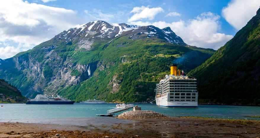 a cruise ship near the shore with a mountain in the background