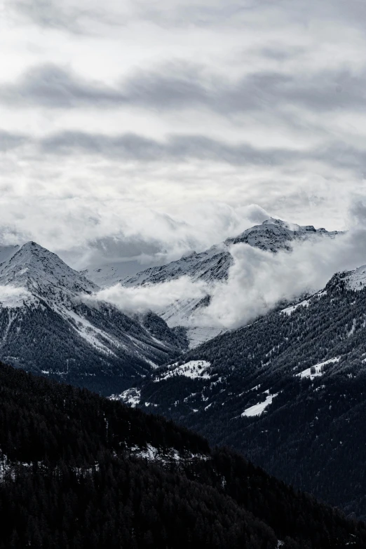 a mountain with snow on the top and low clouds