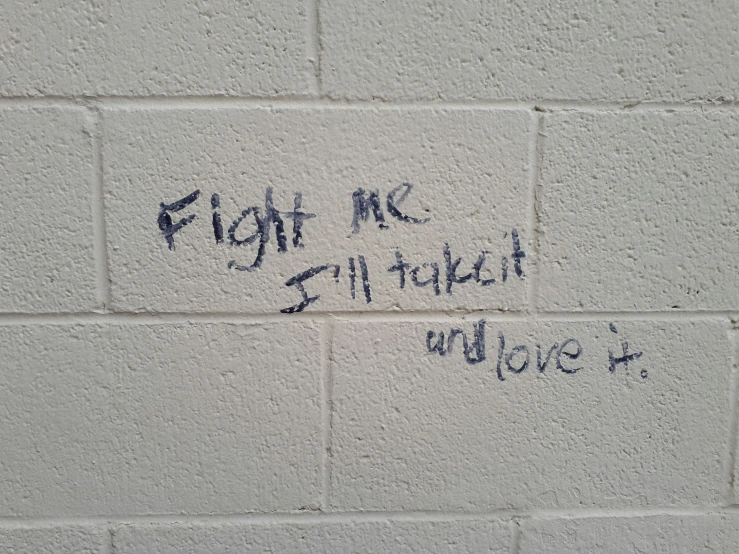 graffiti written on a white brick wall that says fight me 5 / 4 / 2
