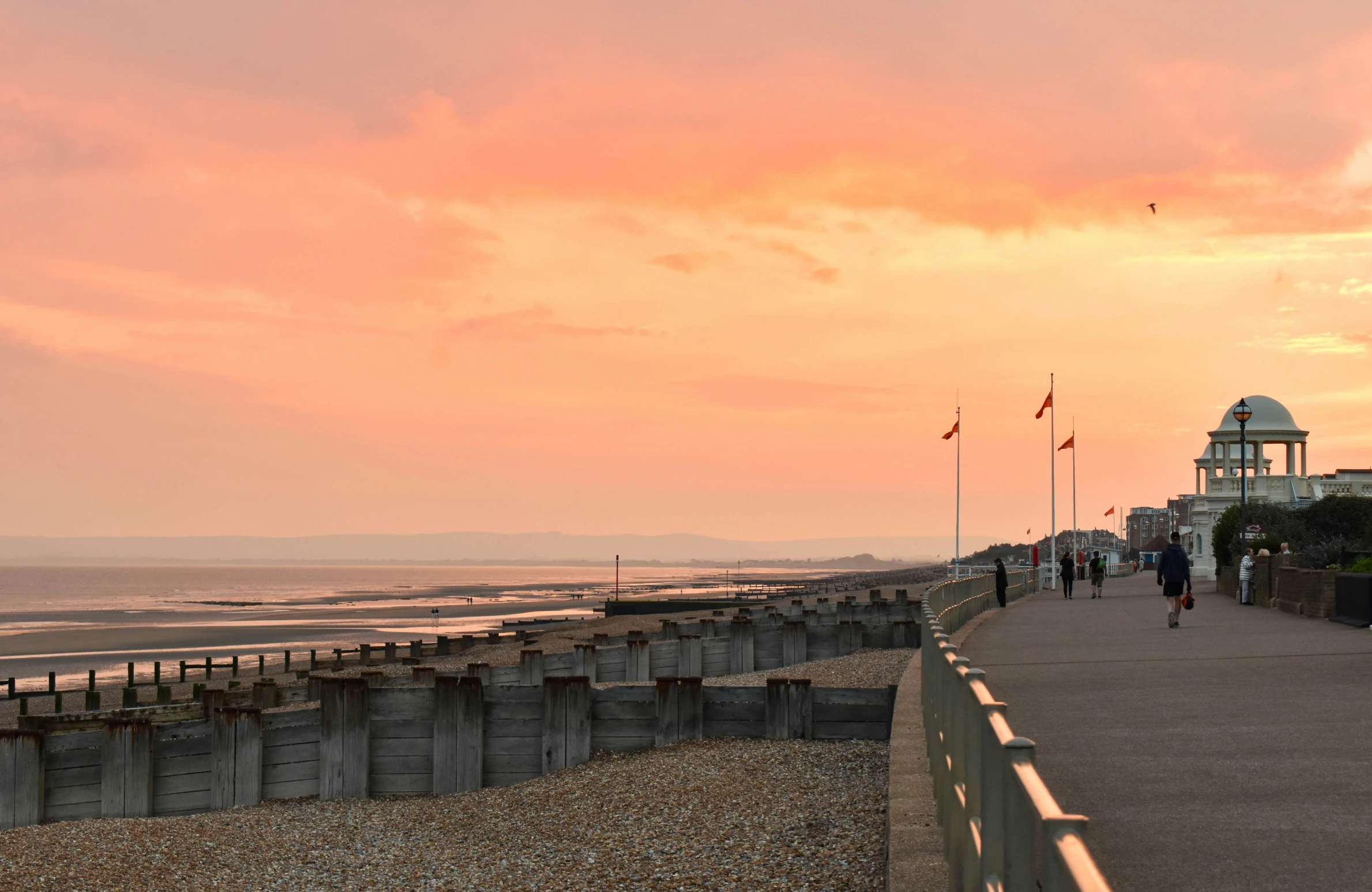 people are walking along the walkway beside the water