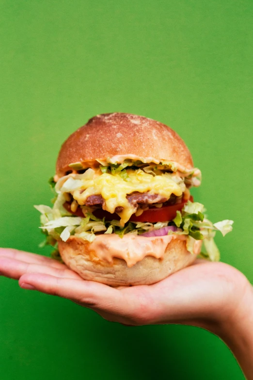 a hand holding a large sandwich made with hamburgers