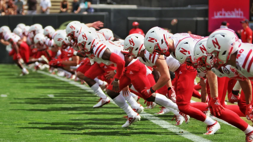 several high school football teams in red uniforms and white helmets on the field