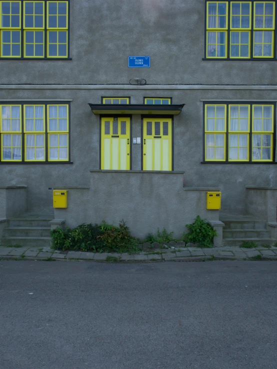 a grey two story building with yellow doors