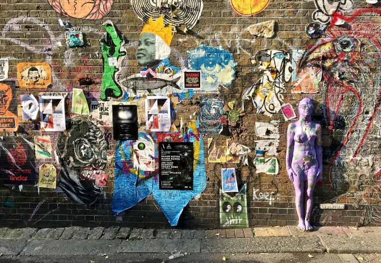 the person is standing next to the brick wall with graffiti