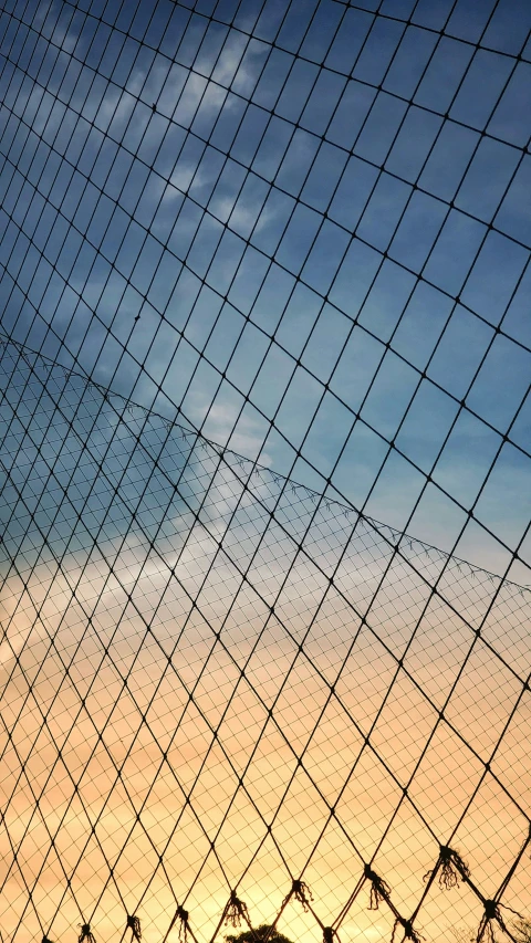 the silhouette of a bird standing on top of a fence