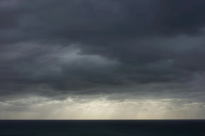 an ocean with a dark and stormy sky and dark clouds