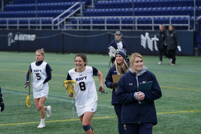 the female lacrosse team is in position on the field