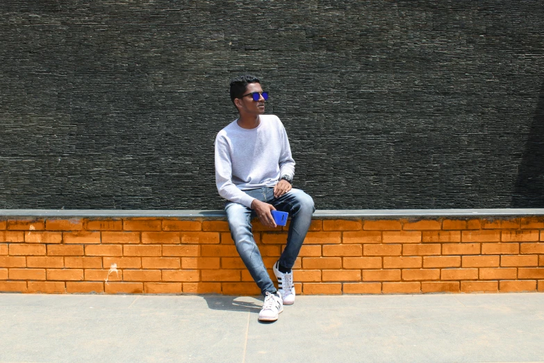 a man sitting on the corner of a brick building