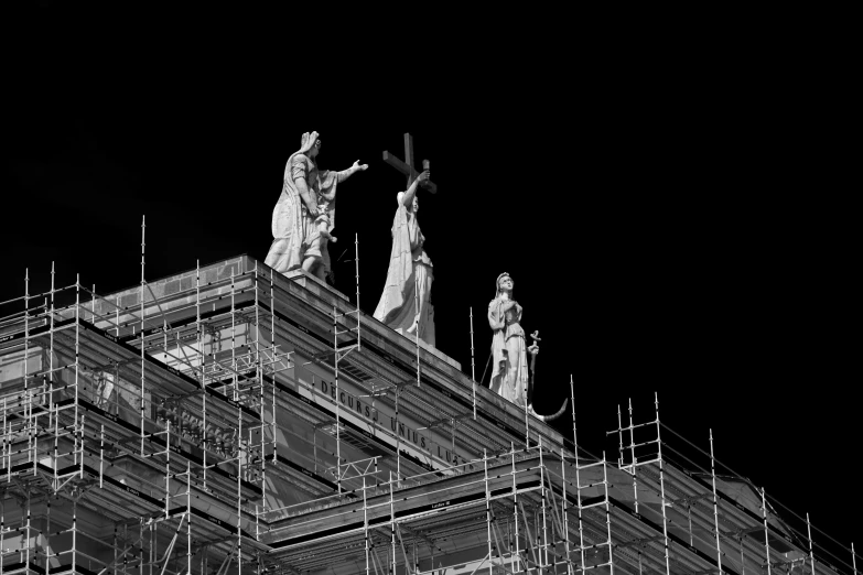 statue atop a tall building at night in black and white