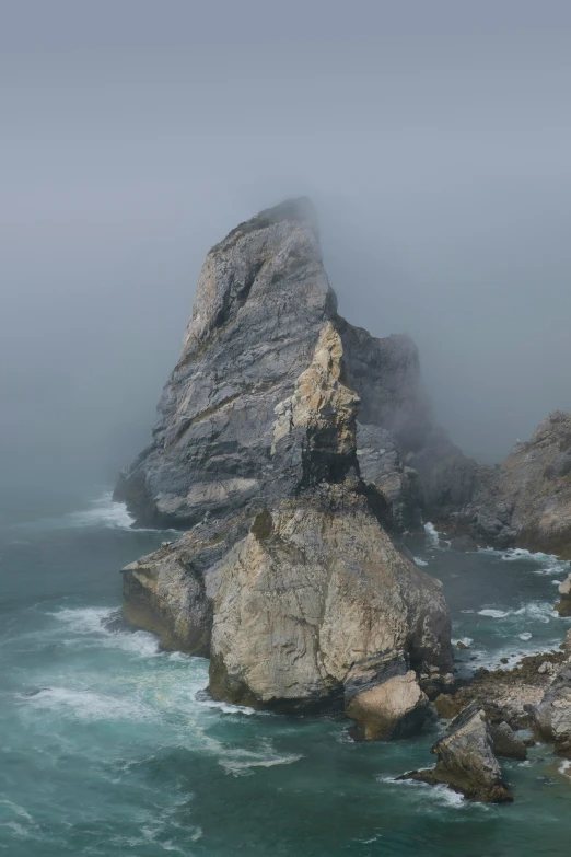 the sea and rocks are covered with fog