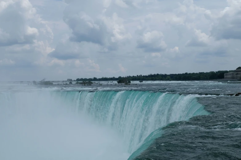 a large waterfall is shown against the cloudy sky