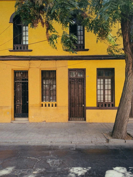 a yellow building with two windows and an umbrella