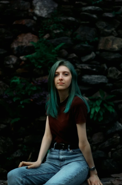 a young woman with green hair sitting in front of rocks