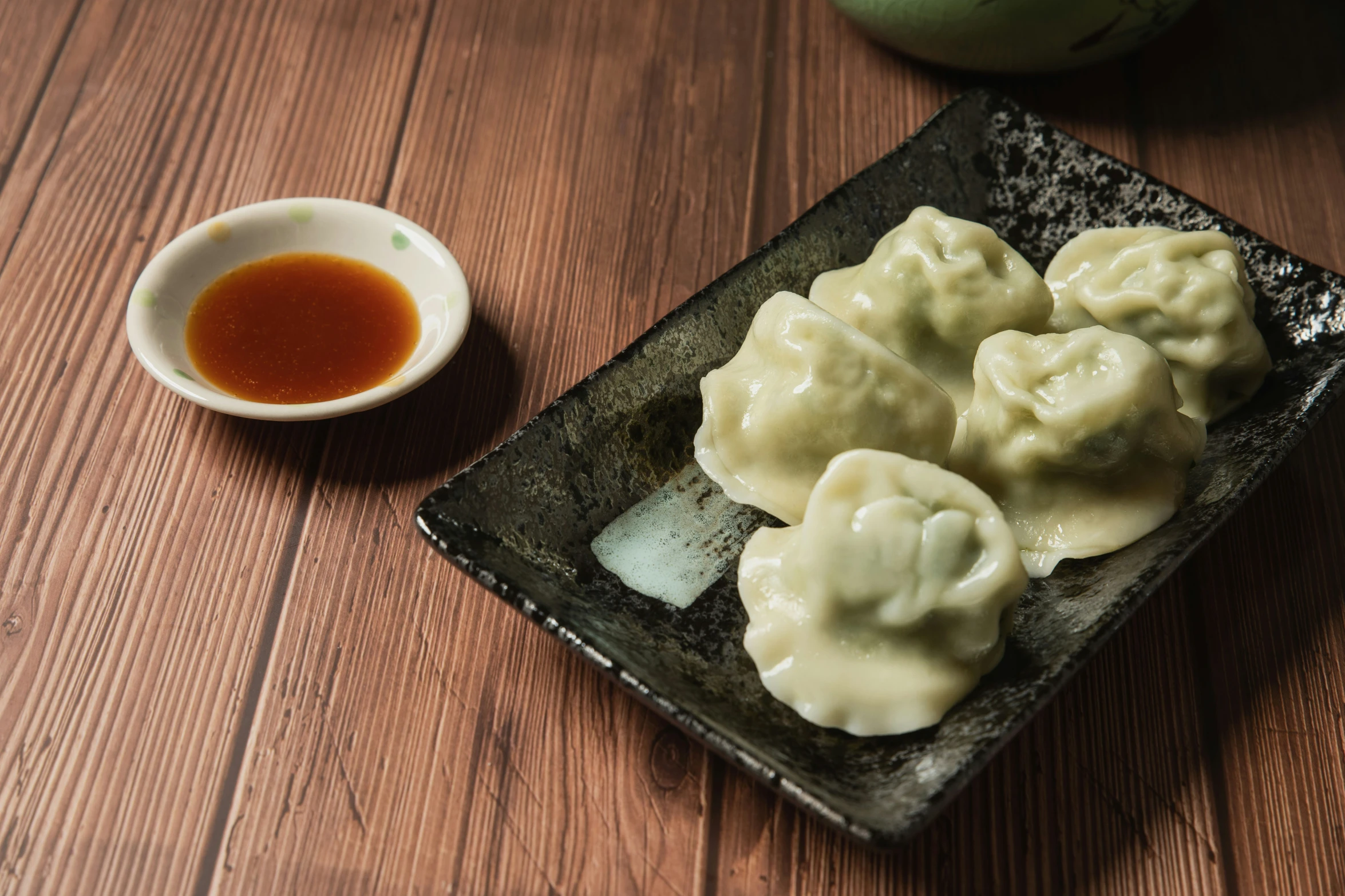 a plate of dumplings is next to a small bowl and sauce
