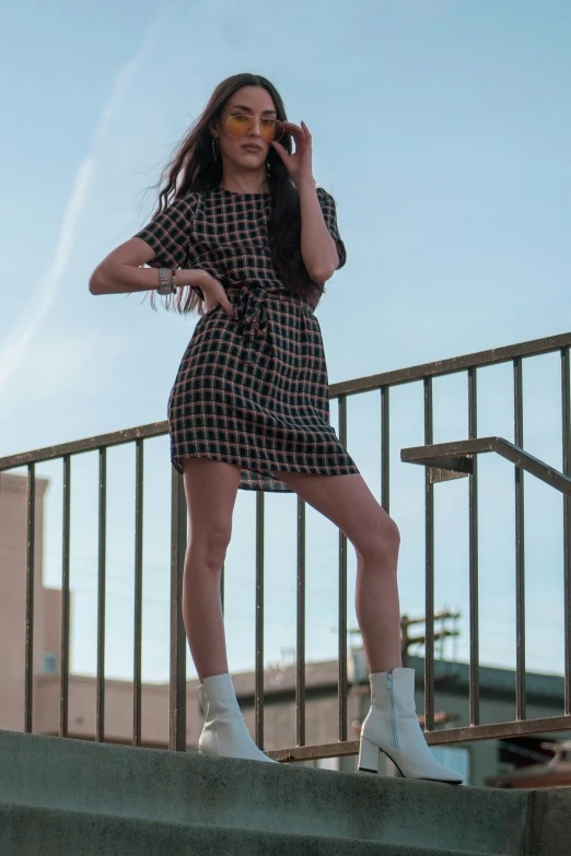 a woman is on the phone outside while wearing a black and white checkered dress