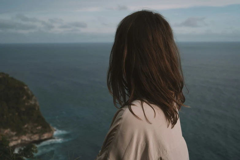 a woman looking out at the ocean from the top of a hill