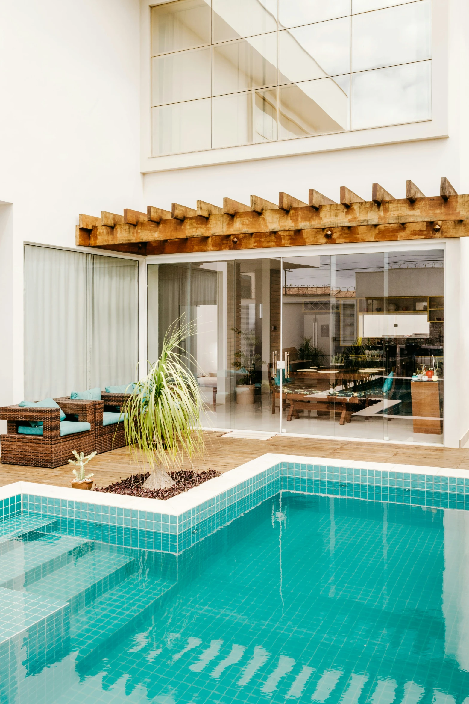 a pool in front of a house with an outdoor dining area