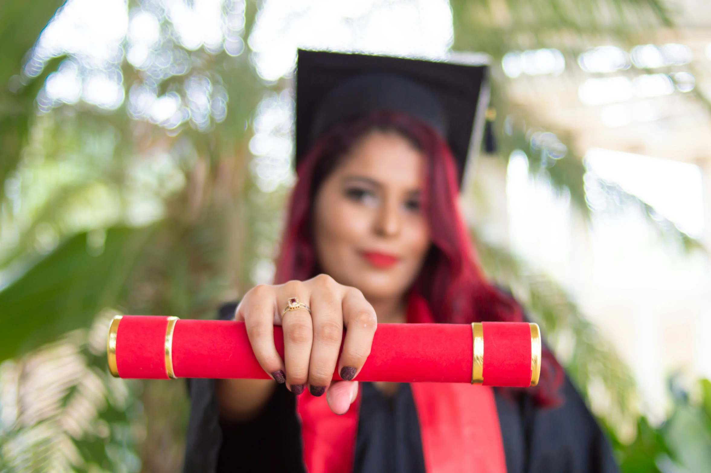 a woman in graduation gown holding onto a red and gold cane