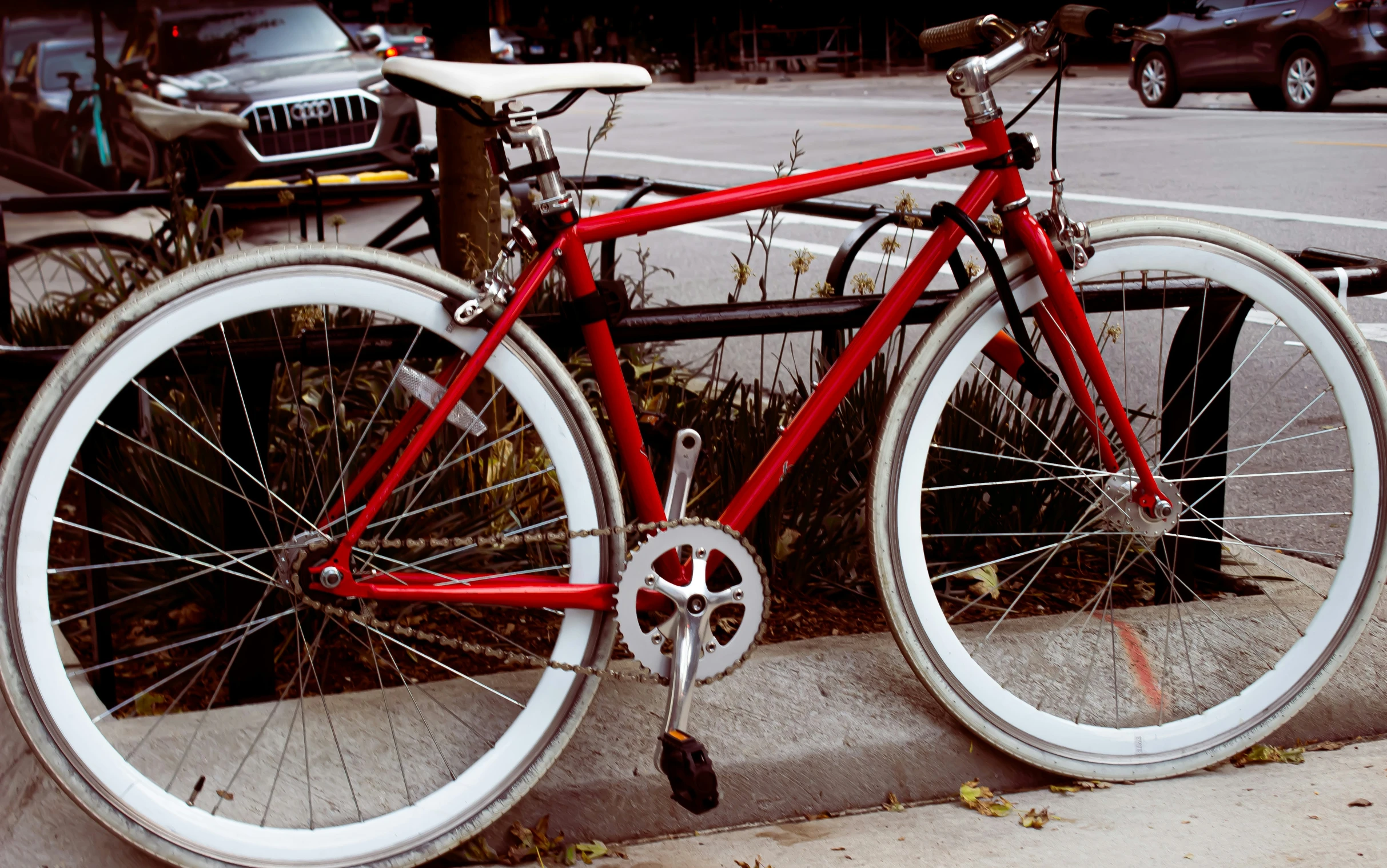 a red bicycle with white rims is parked on the curb