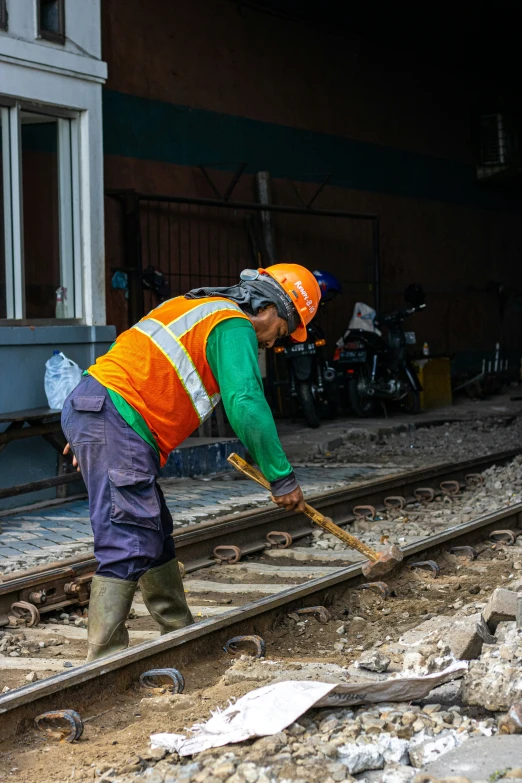 a man in green and orange jacket working on a railroad