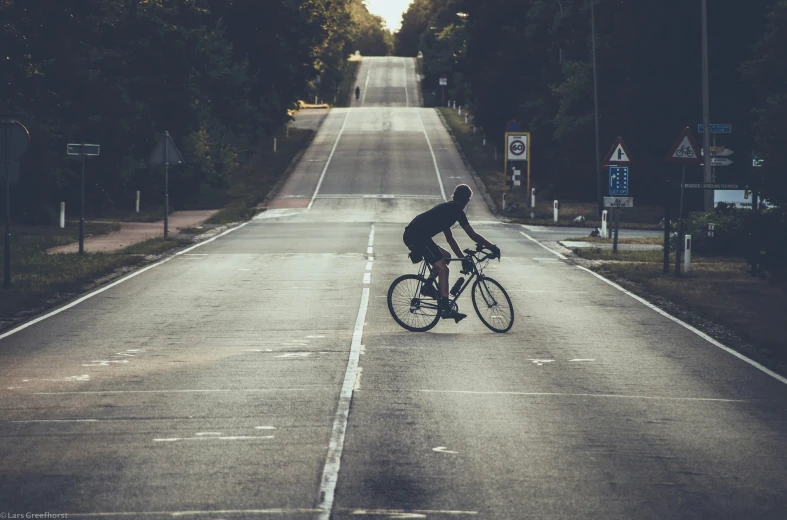 there is a man riding his bicycle down the street