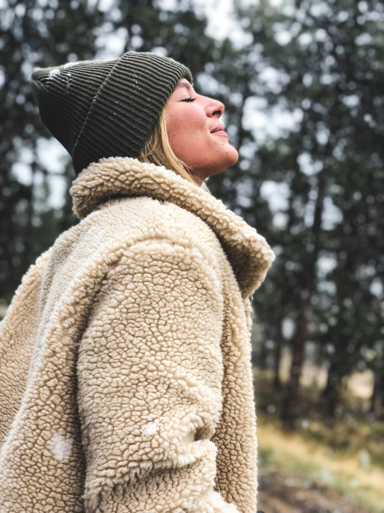 a woman wearing a coat with hood and hat on