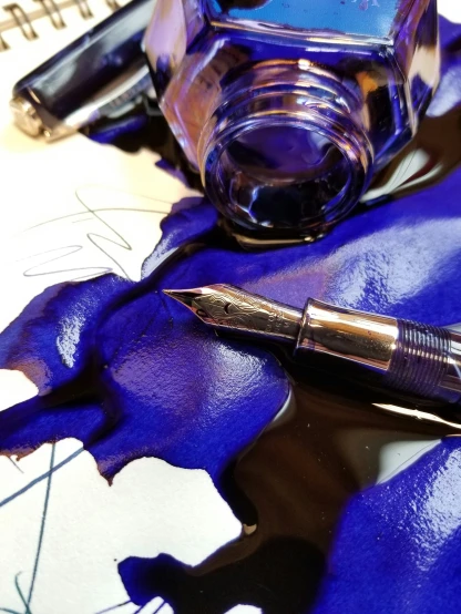 a fountain pen resting on an ink pot of ink